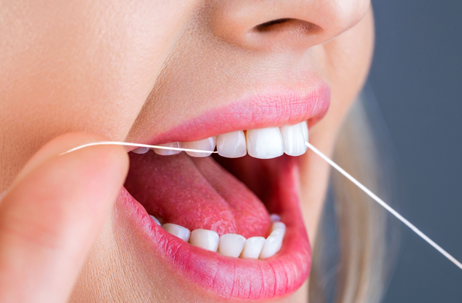 Close-up of a person flossing their teeth.