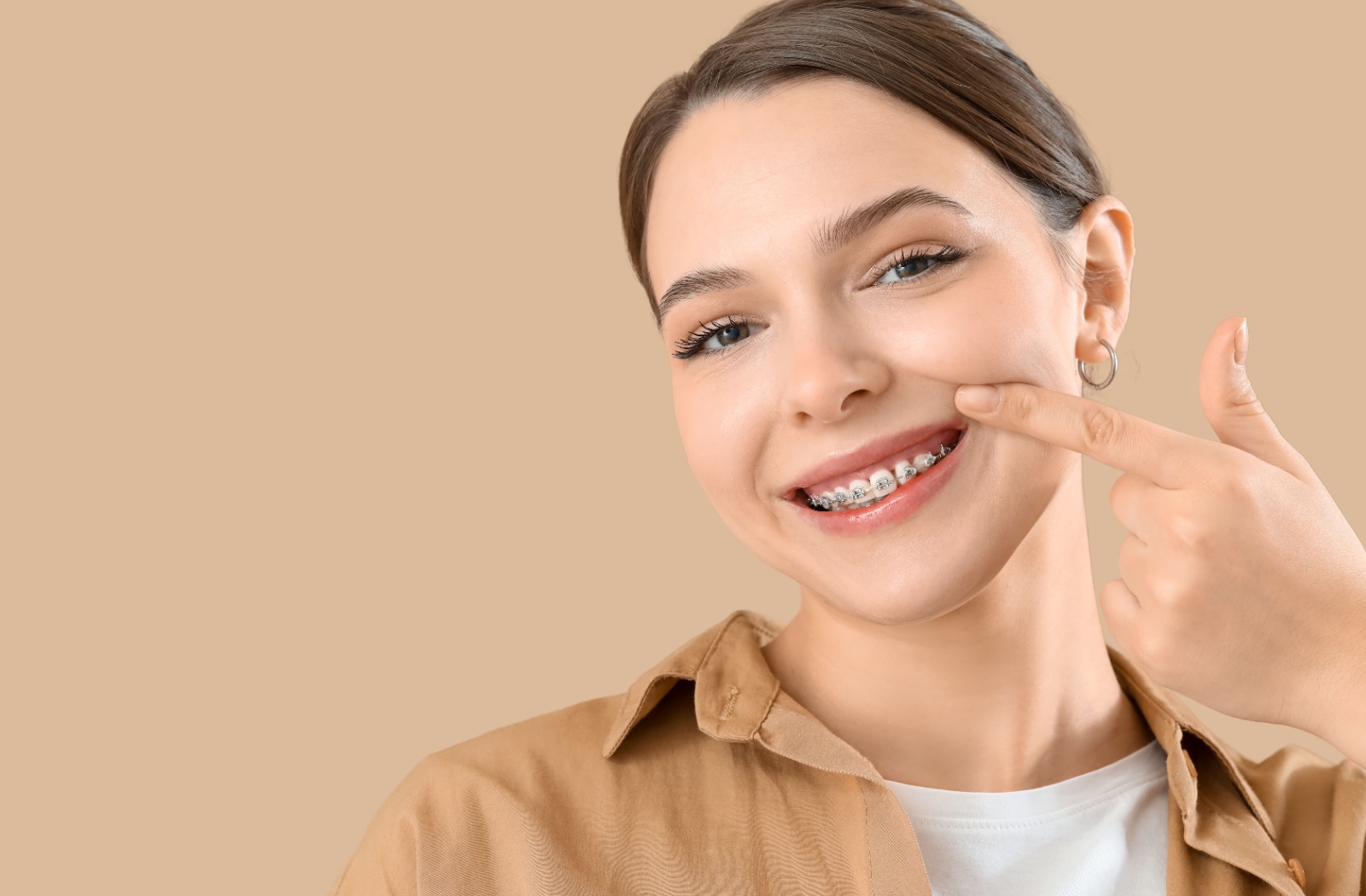 Person smiling and pointing to their braces.