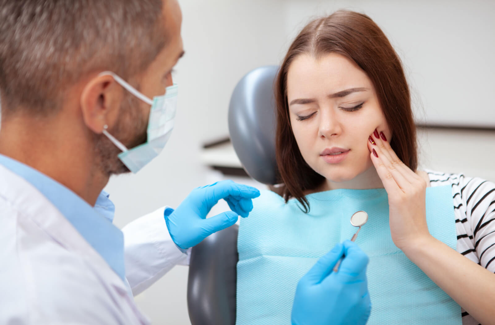 Femme indiquant un mal de dent à son dentiste